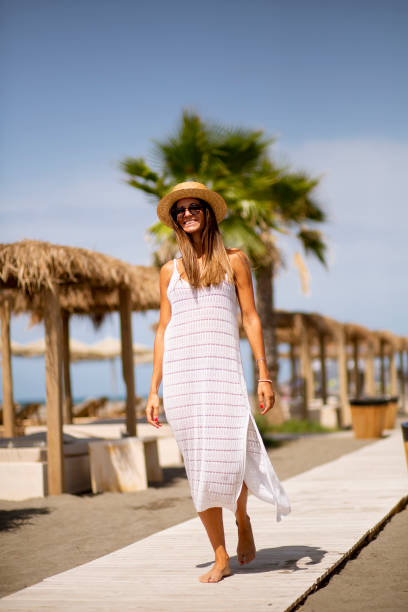Pretty young woman walking on a beach at summer