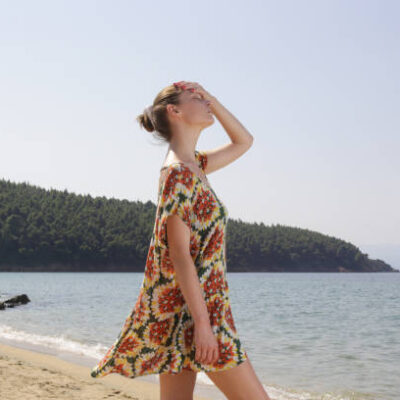 Girl wearing wide floral dress on the beach. summer fashion clothes.