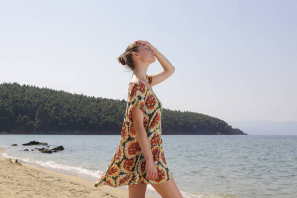 Girl wearing wide floral dress on the beach. summer fashion clothes.