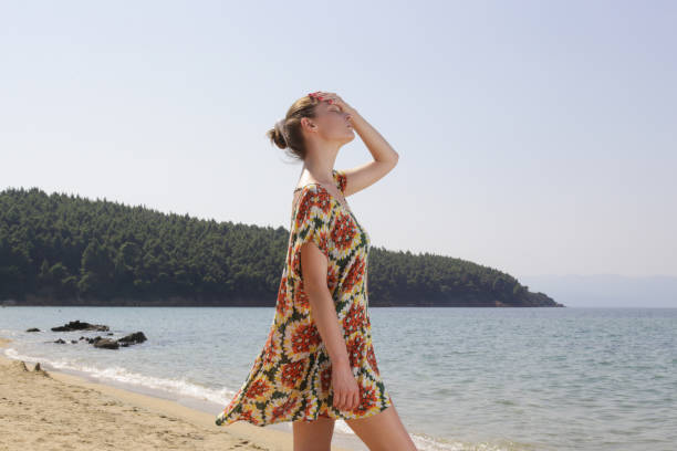 Girl wearing wide floral dress on the beach. summer fashion clothes.