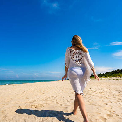 Beautiful middle aged woman walking on sandy beach in summertime. back view